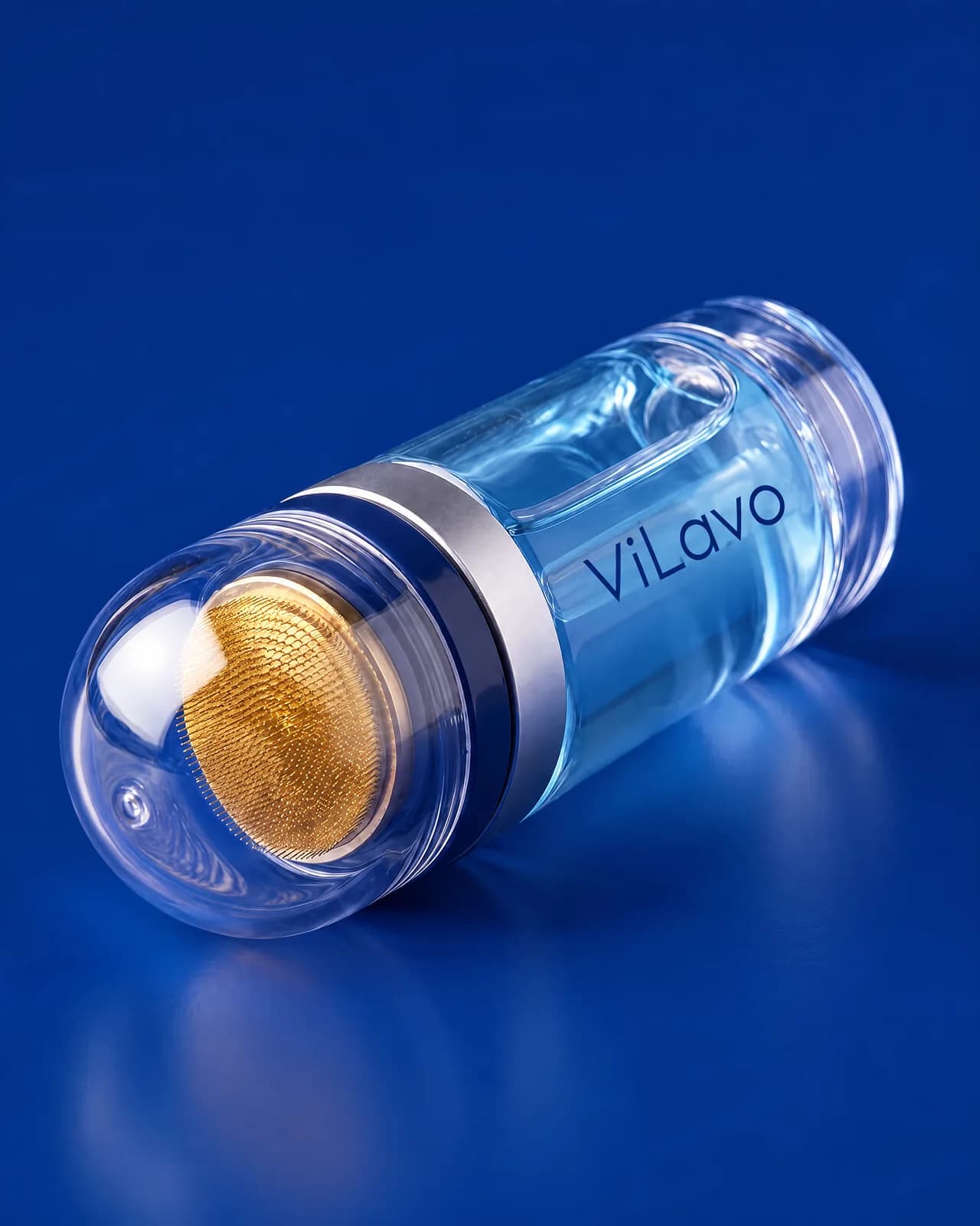 Macro of the ViLavo applicator's gold-plated micro-needle pad under its clear dome on a deep blue ground